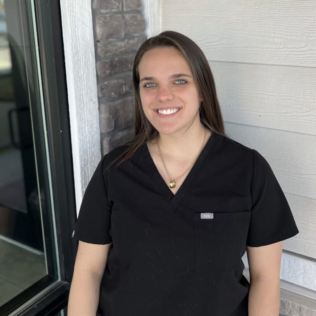 female with long brown hearing and blue eyes wearing black scrubs