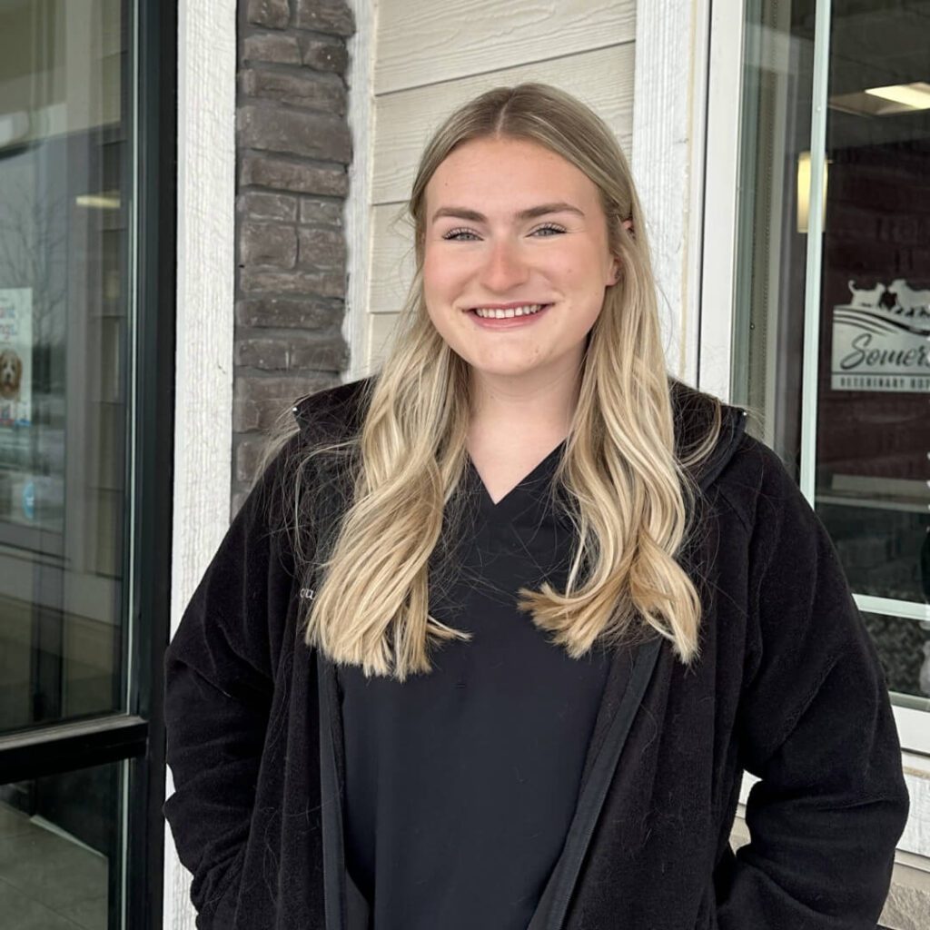 female with long blonde hair wearing a black fleece jacket and black scrubs